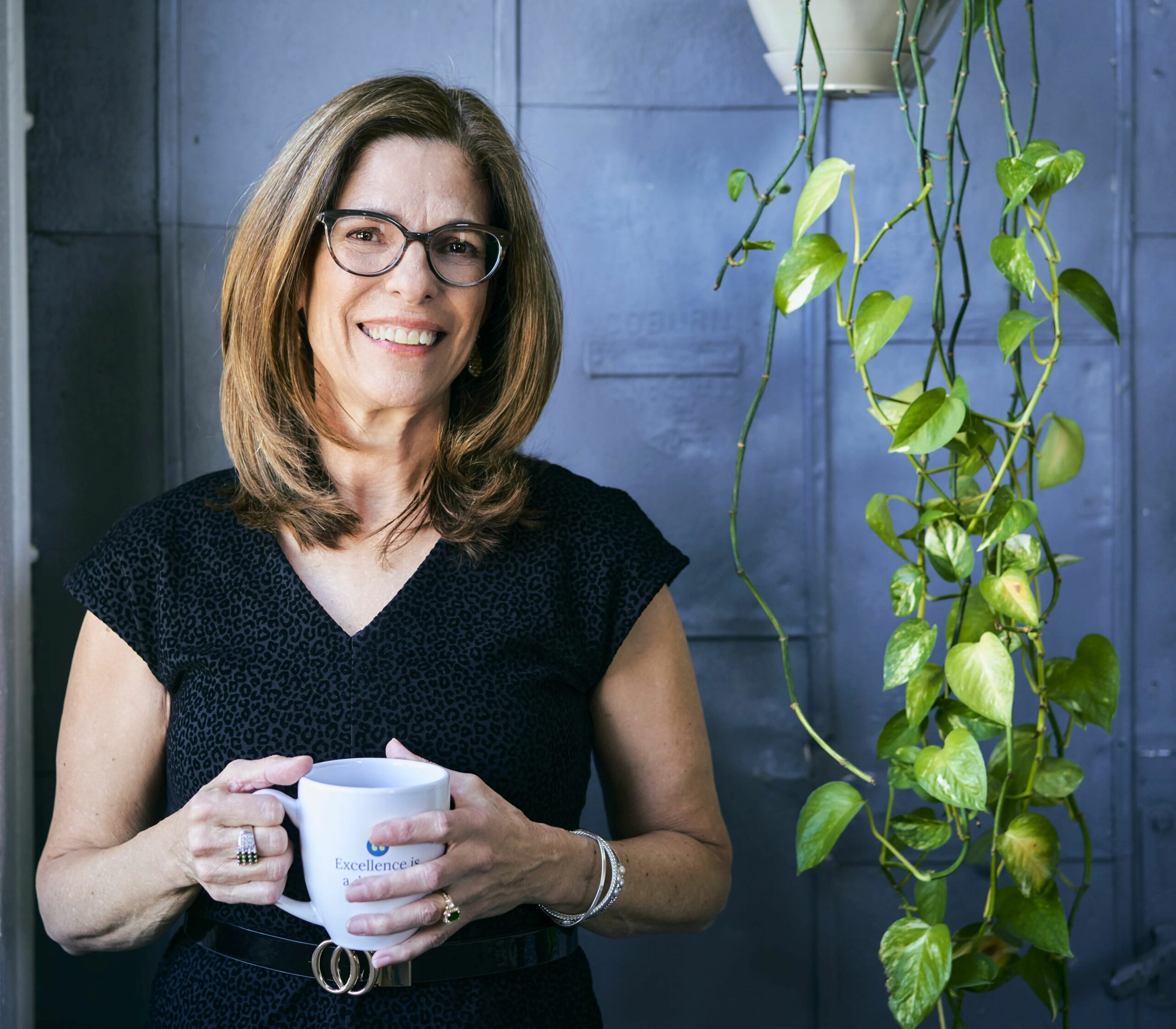 LuAnn Nigara, RESACON speaker and business coach, smiling while holding a coffee mug, sharing insights on overcoming pricing objections in home staging.